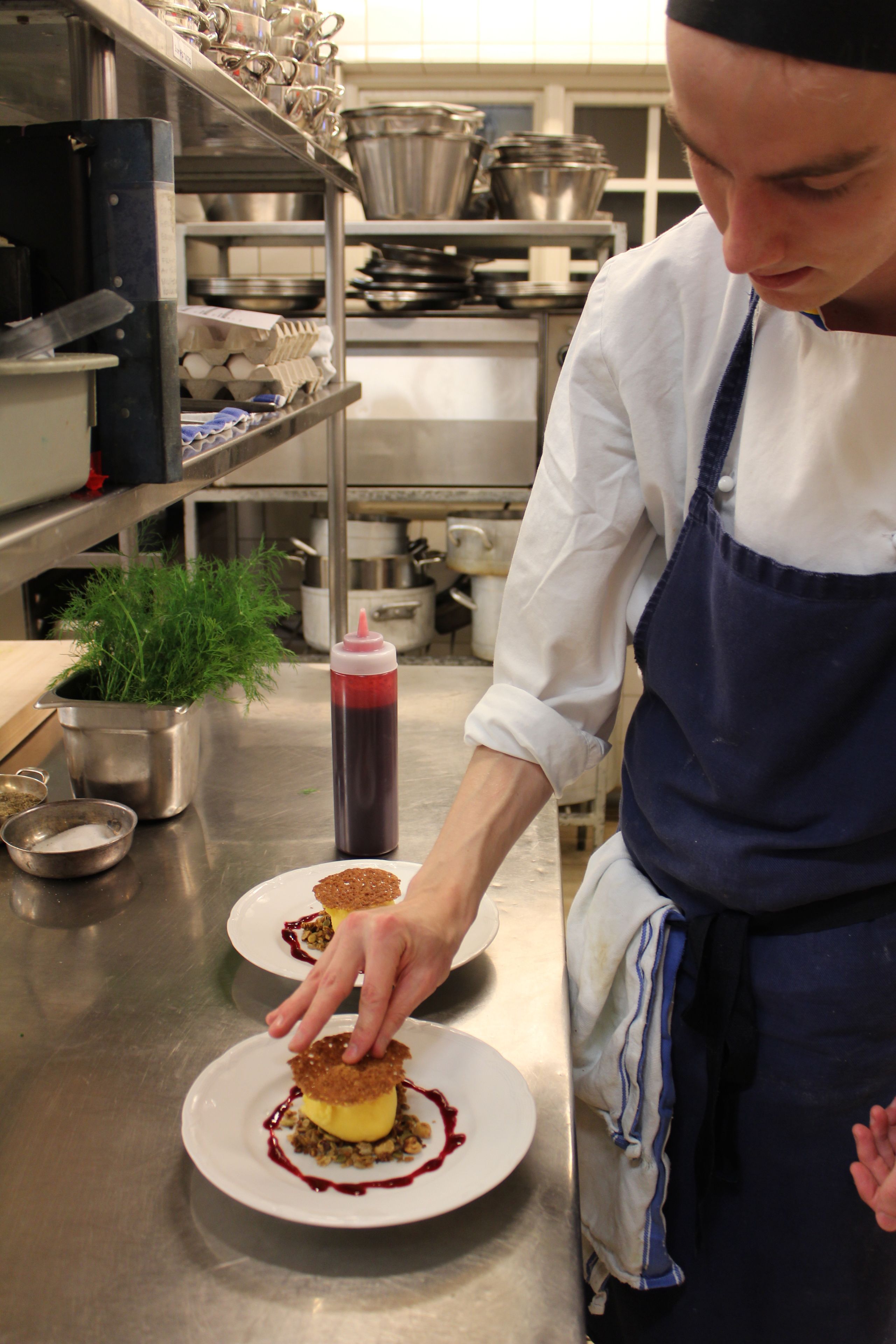 Un chef en una cocina profesional preparando un postre.