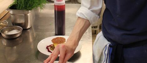 A chef in a professional kitchen preparing a dessert.
