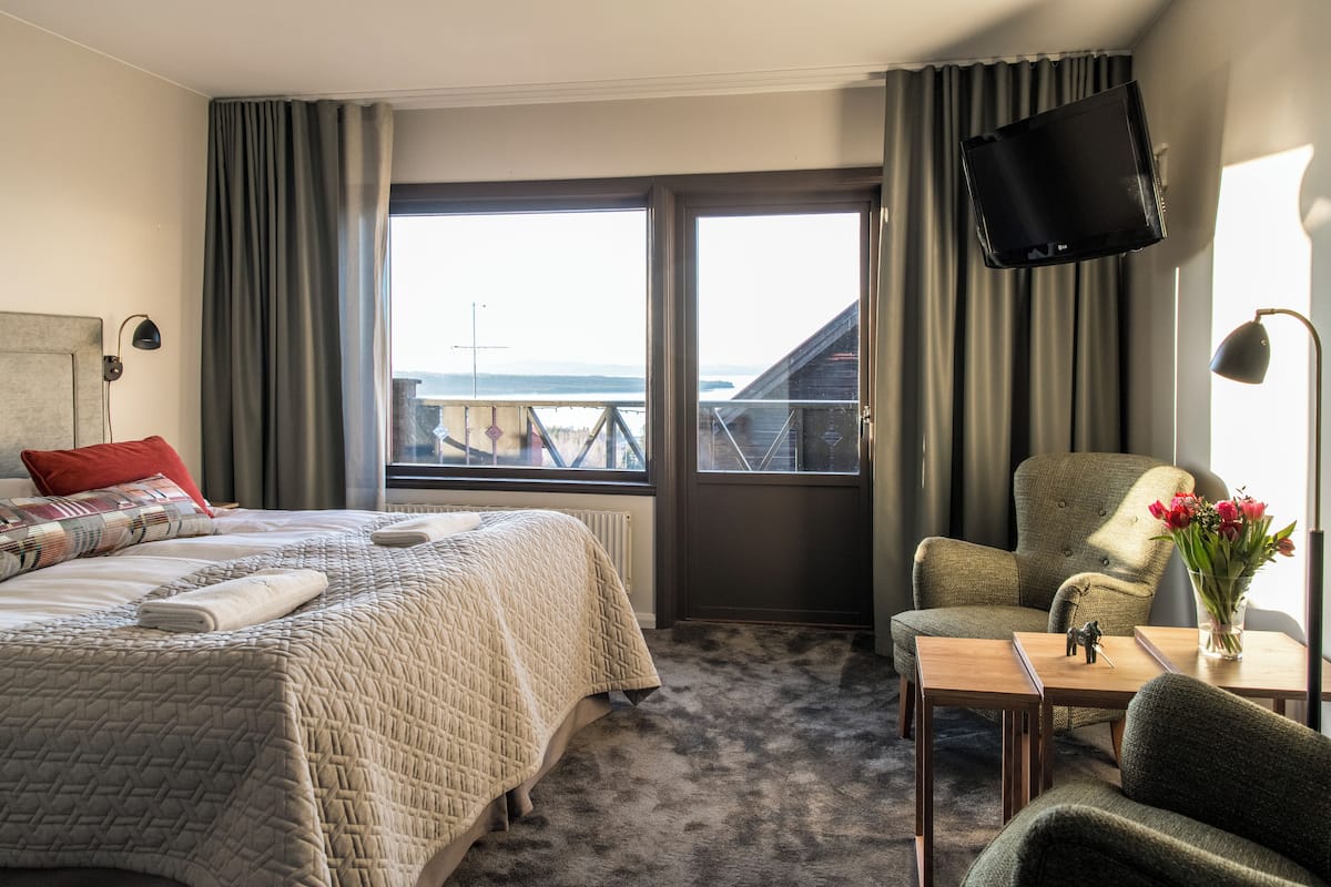 Habitación de hotel con cama, una silla, una mesa, televisor y vistas al exterior.