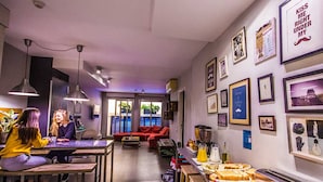 A modern living space with a dining area, kitchen, and seating area. - Don Moustache Hostel (Barcelona)
