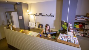 A reception desk with a sign reading "donMoustache!" and a display of craft beer boxes. - Don Moustache Hostel (Barcelona)