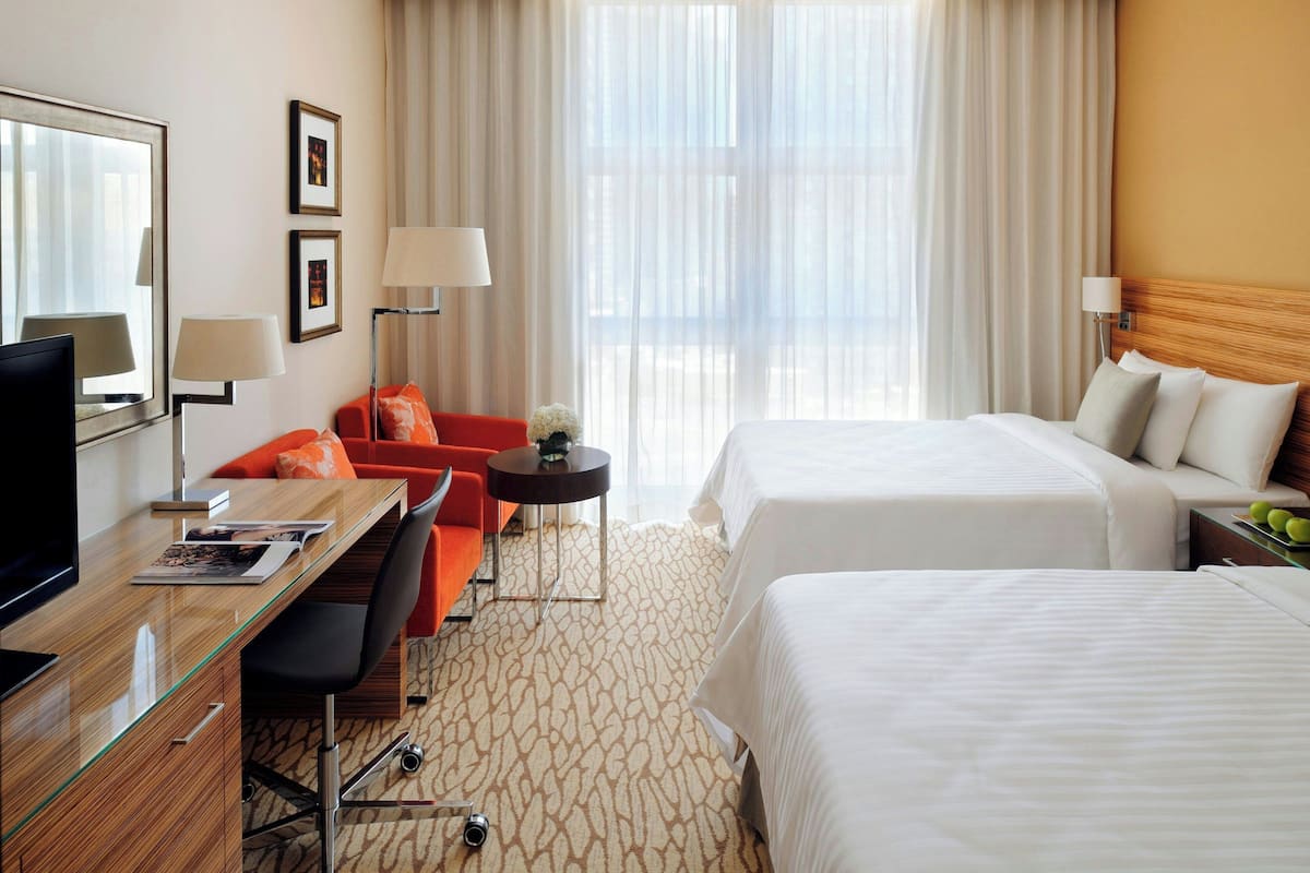 Ein Hotelzimmer mit einem Holztisch, zwei Betten, einer Couch, einem kleinen Tisch und einem Fernseher.