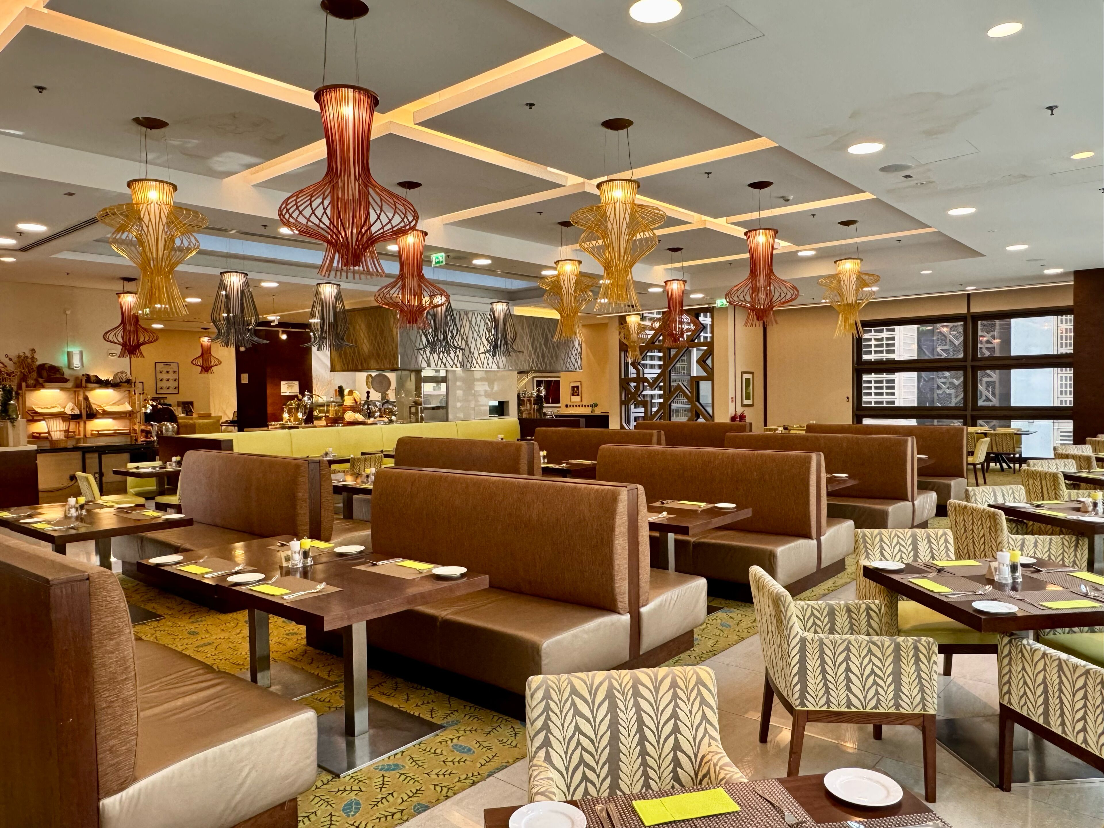 A hotel lobby with seating areas, tables, and modern lighting fixtures.