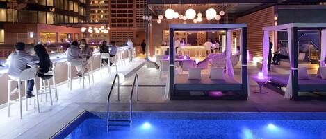 Un bar en la azotea con piscina, zonas de estar y barra.