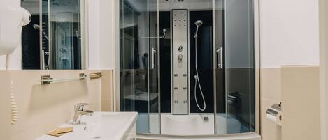 Un baño moderno con ducha de vidrio, un lavabo blanco y un espejo.