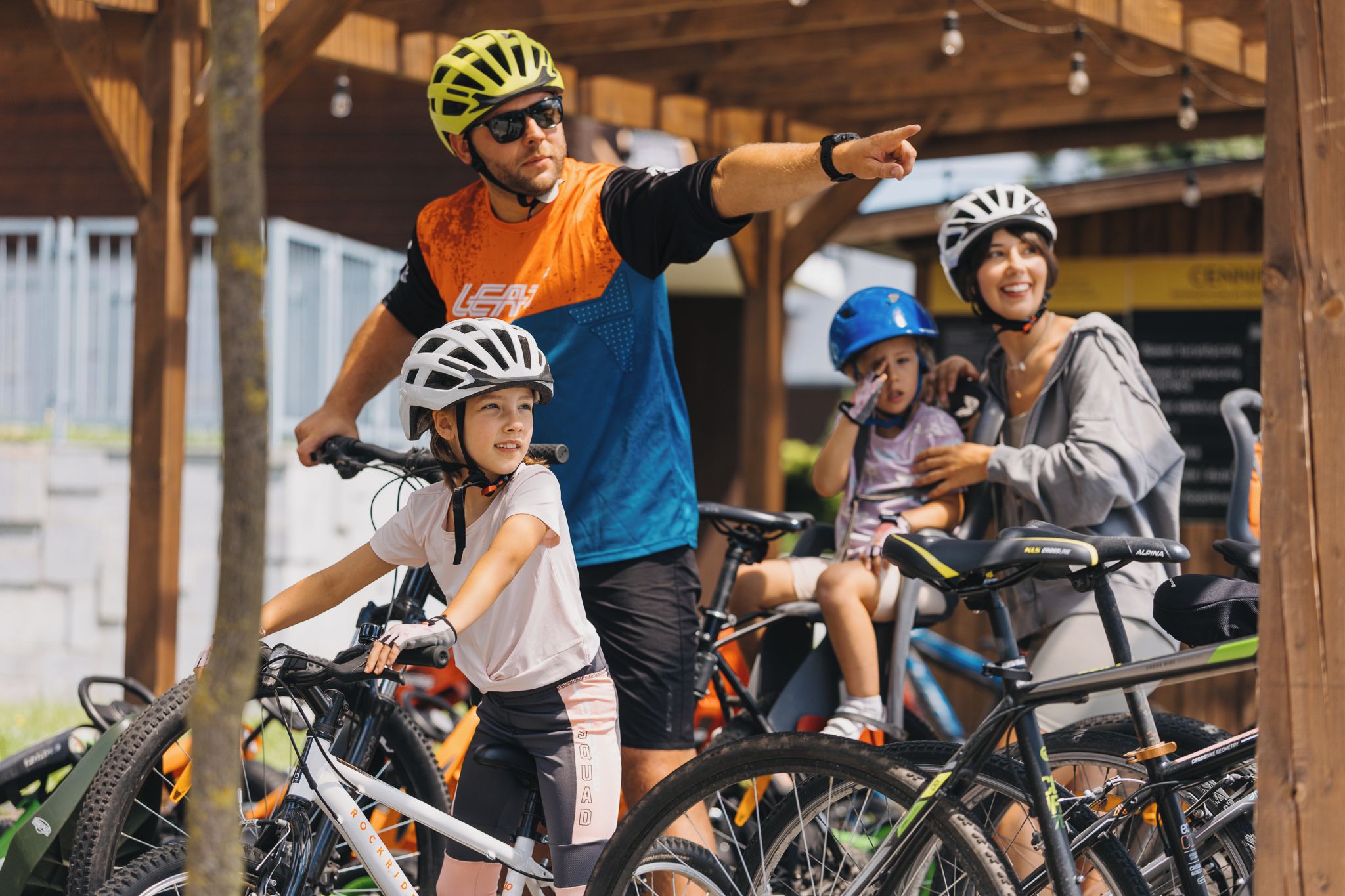 A covered outdoor area with bicycles and people, including children and adults.