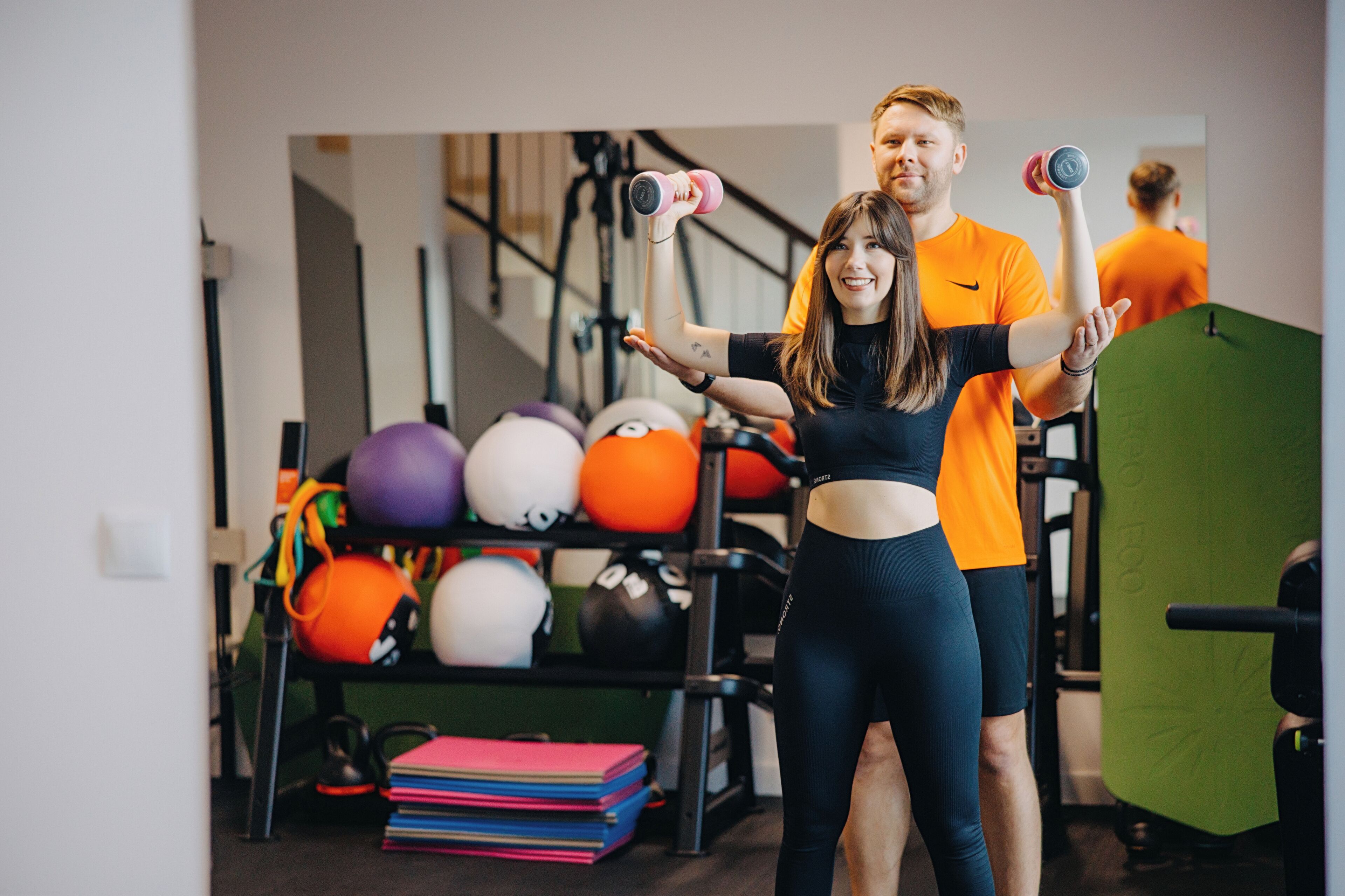 Een fitnessruimte met trainingsapparatuur, waaronder gewichten en medicine ballen.