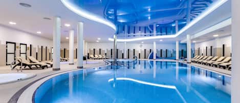 Una piscina techada, una piscina al aire libre, sombrillas