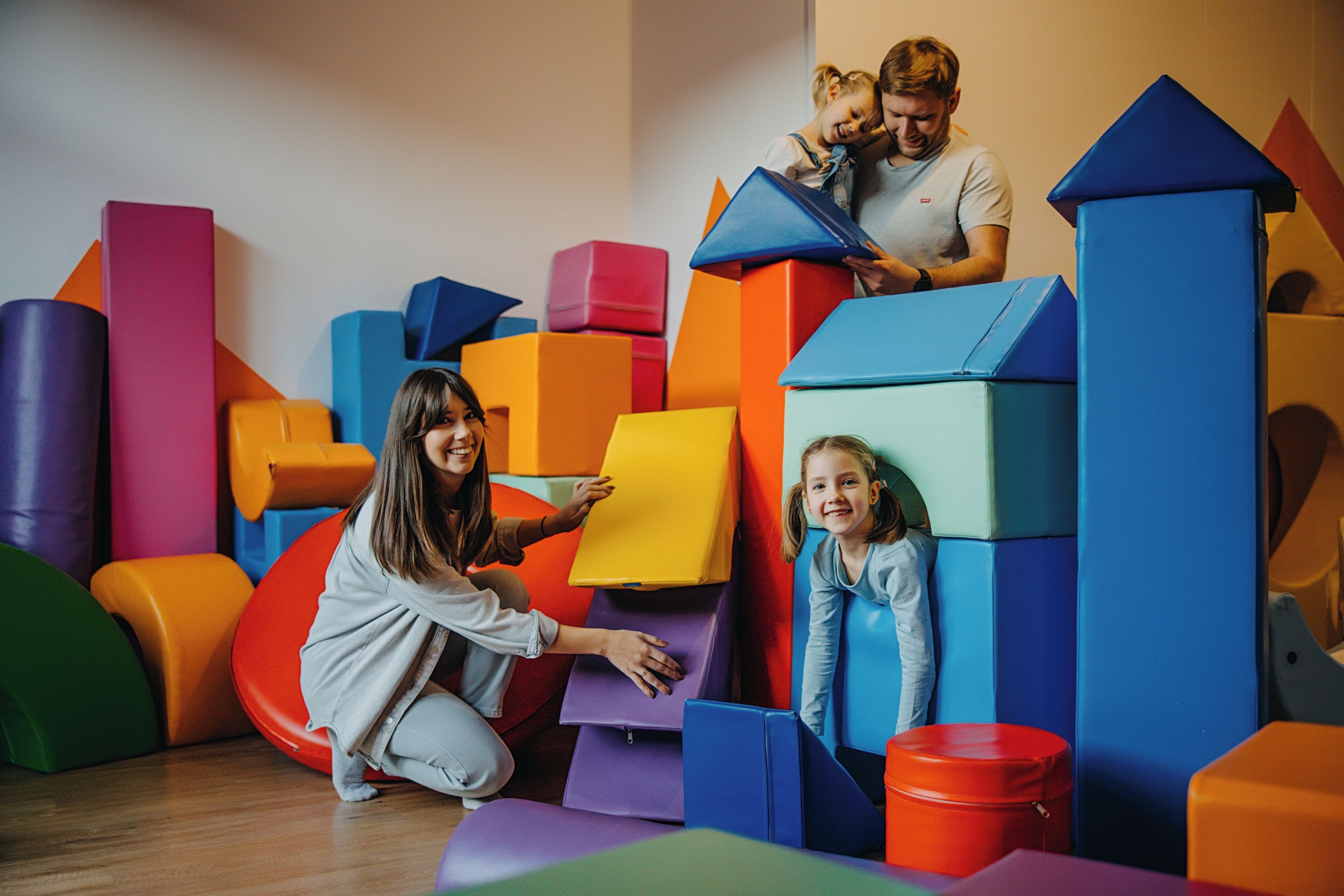 Een speelruimte met kleurrijke foam blokken en een kind dat er op klimt.