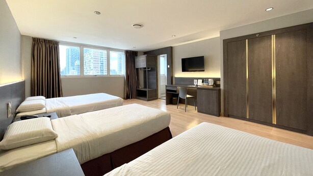 Ein Hotelzimmer mit zwei Betten, einem Schreibtisch, einem Fernseher und einem Kleiderschrank.