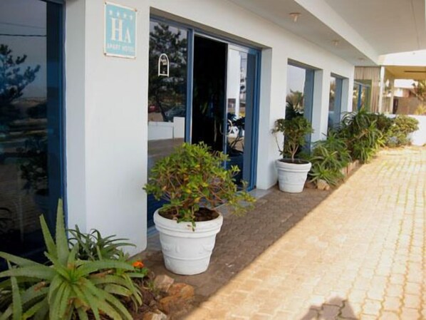 A hotel entrance with a paved walkway, potted plants, and a sign indicating a spa facility.