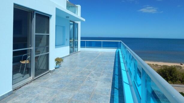 A modern building with a balcony overlooking a beach and the ocean. - Apart Hotel Punta Azul (Punta del Este)