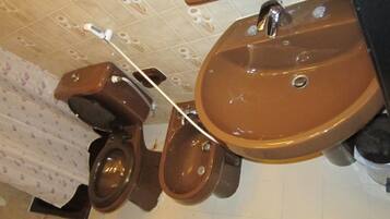 Un baño con un lavabo marrón, un inodoro y un bidé.
