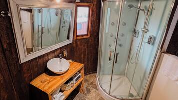 A bathroom with a wooden interior, a glass shower enclosure, a white sink, and a toilet.