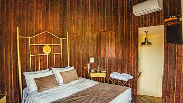 A wooden-paneled room with a bed, a bedside table, a lamp, and an air conditioning unit.