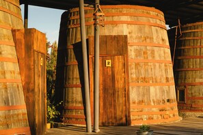 Grandes tanques de madera cilíndricos con tuberías metálicas, numerados 2 y 3, y una puerta de madera.