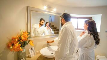 Une salle de bain avec un grand miroir, un lavabo et un vase rempli de fleurs.