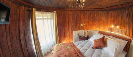 A wooden-paneled room with a bed, a chandelier, and a telephone on the nightstand.