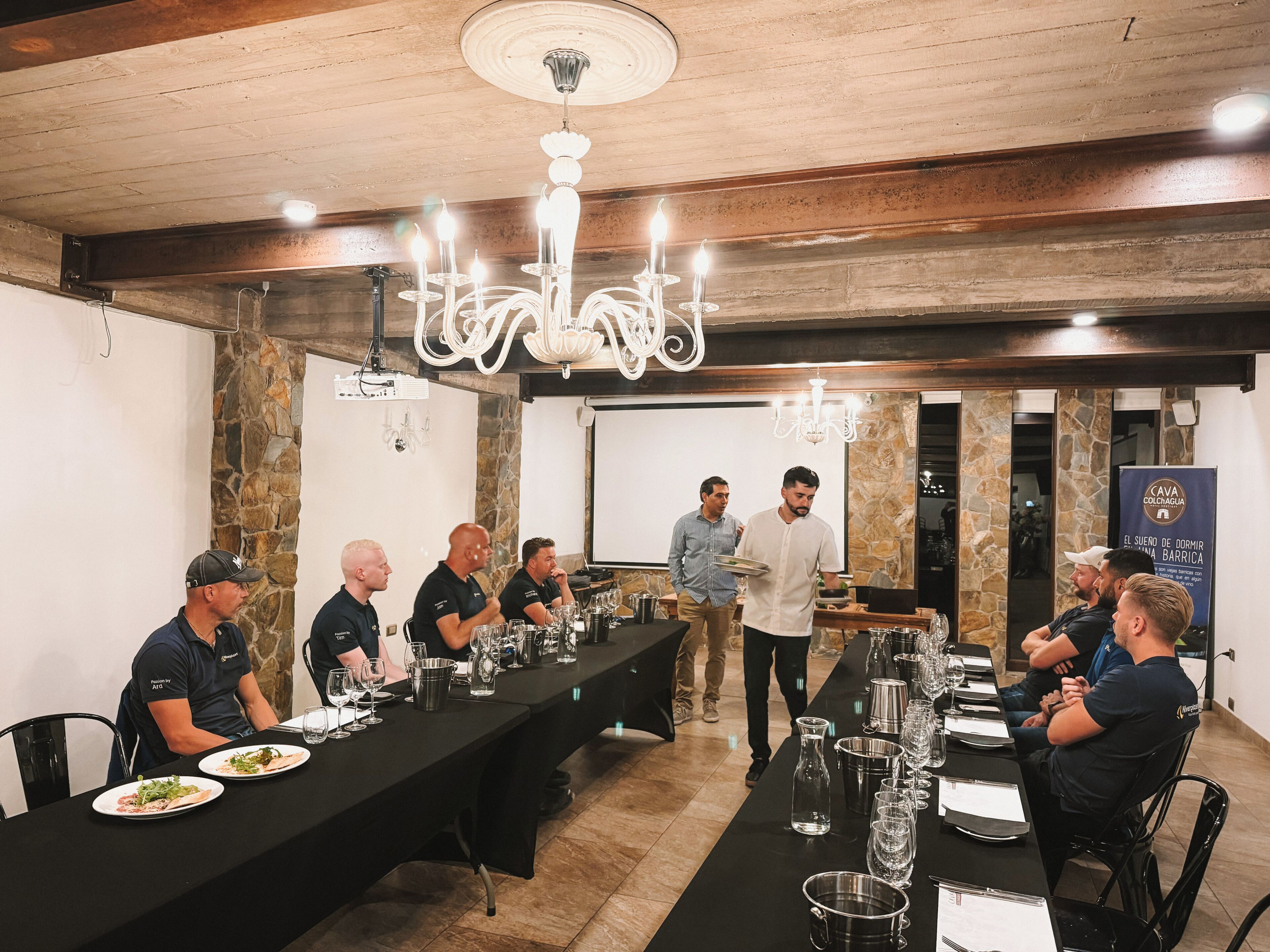 Un salón de conferencias con una mesa larga, sillas y una pantalla proyectora.