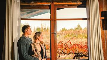A couple standing by a window with a view of autumn leaves.