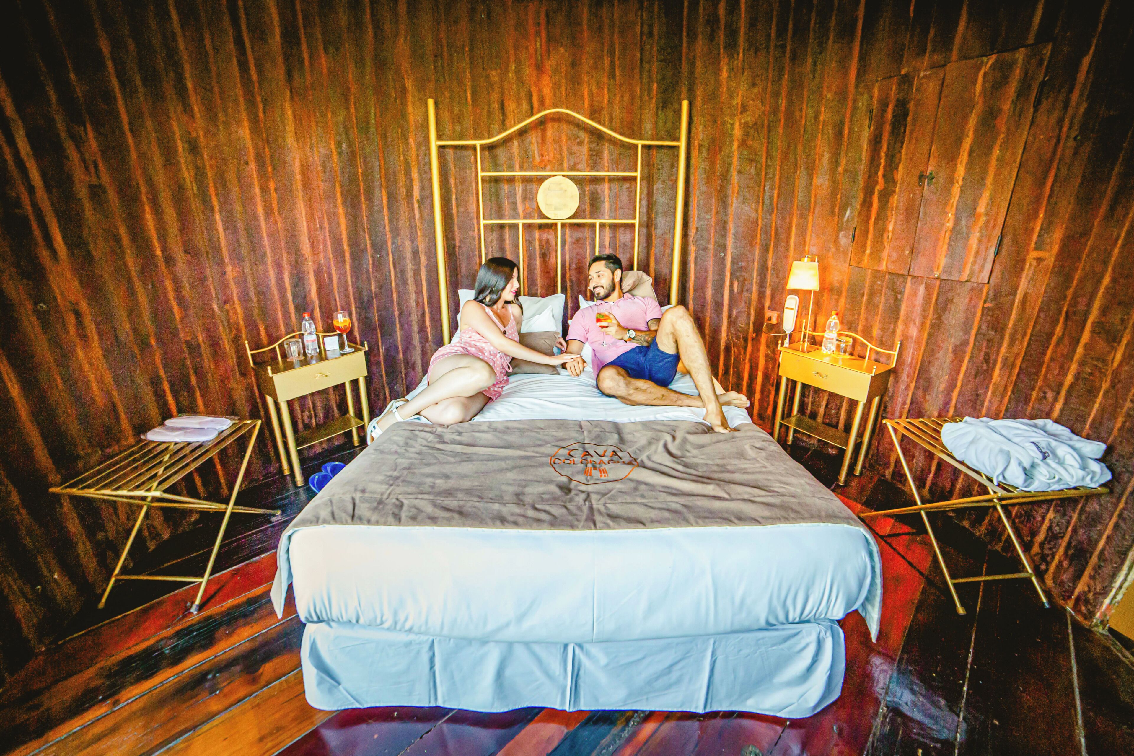 Una cama con cabecera, dos mesitas de noche y una pared con paneles de madera.