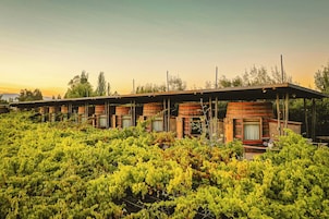Una hilera de cabañas de estilo rústico con un paseo techado, rodeadas de exuberante vegetación.