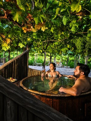 A hot tub with a wooden deck, surrounded by trees and greenery. - Hotel Cava Colchagua (Santa Cruz)