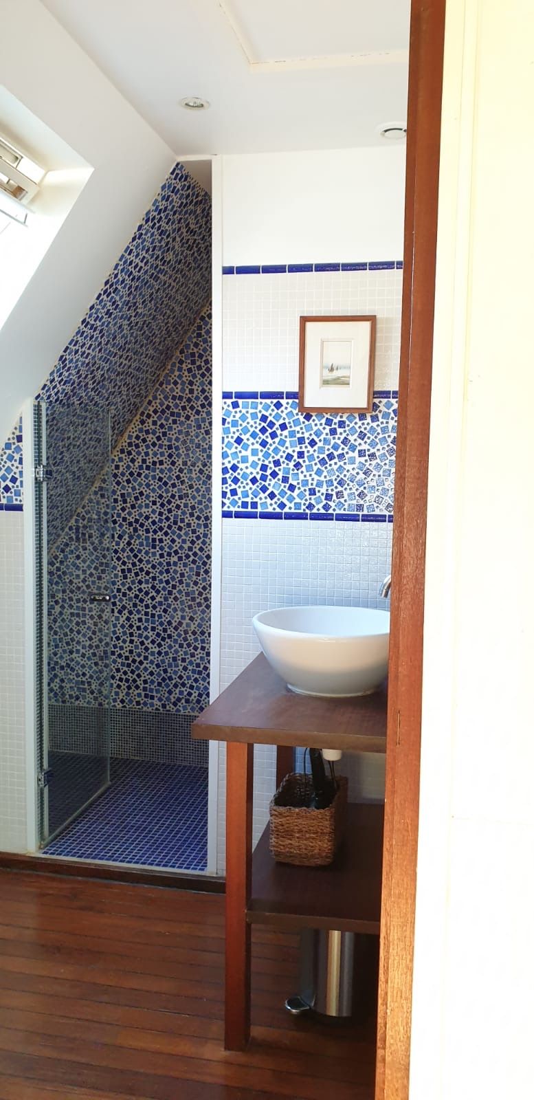 A bathroom with a tiled wall, a white sink, and a wooden floor.