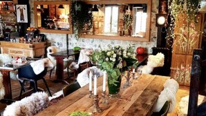 A rustic dining area with a wooden table, green moss decorations, and white furry chairs. - La Cour Sainte Catherine (Honfleur)