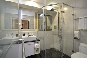 Ein modernes Badezimmer mit Duschkabine aus Glas, Waschbecken mit Toilettenartikeln und Toilette.