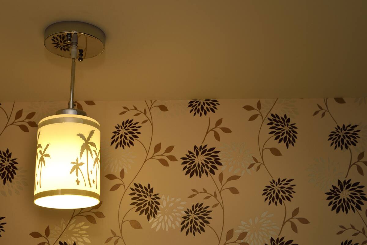 A ceiling light fixture with a floral pattern on the wall.