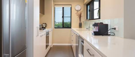 A modern kitchen with stainless steel appliances, a window with a view, and a clock on the wall.