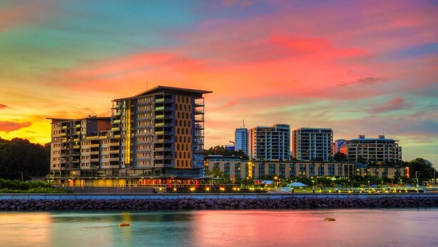 Hotel aan het water met meerdere hoge gebouwen, een jachthaven en een zonsondergang.