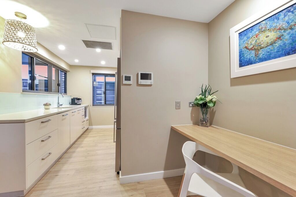 A modern kitchen with a wooden countertop, a sink, and a dining area with a white chair.