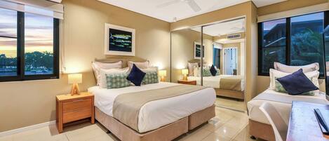 A modern hotel room with a large bed, bedside tables, a desk, and a large mirror.