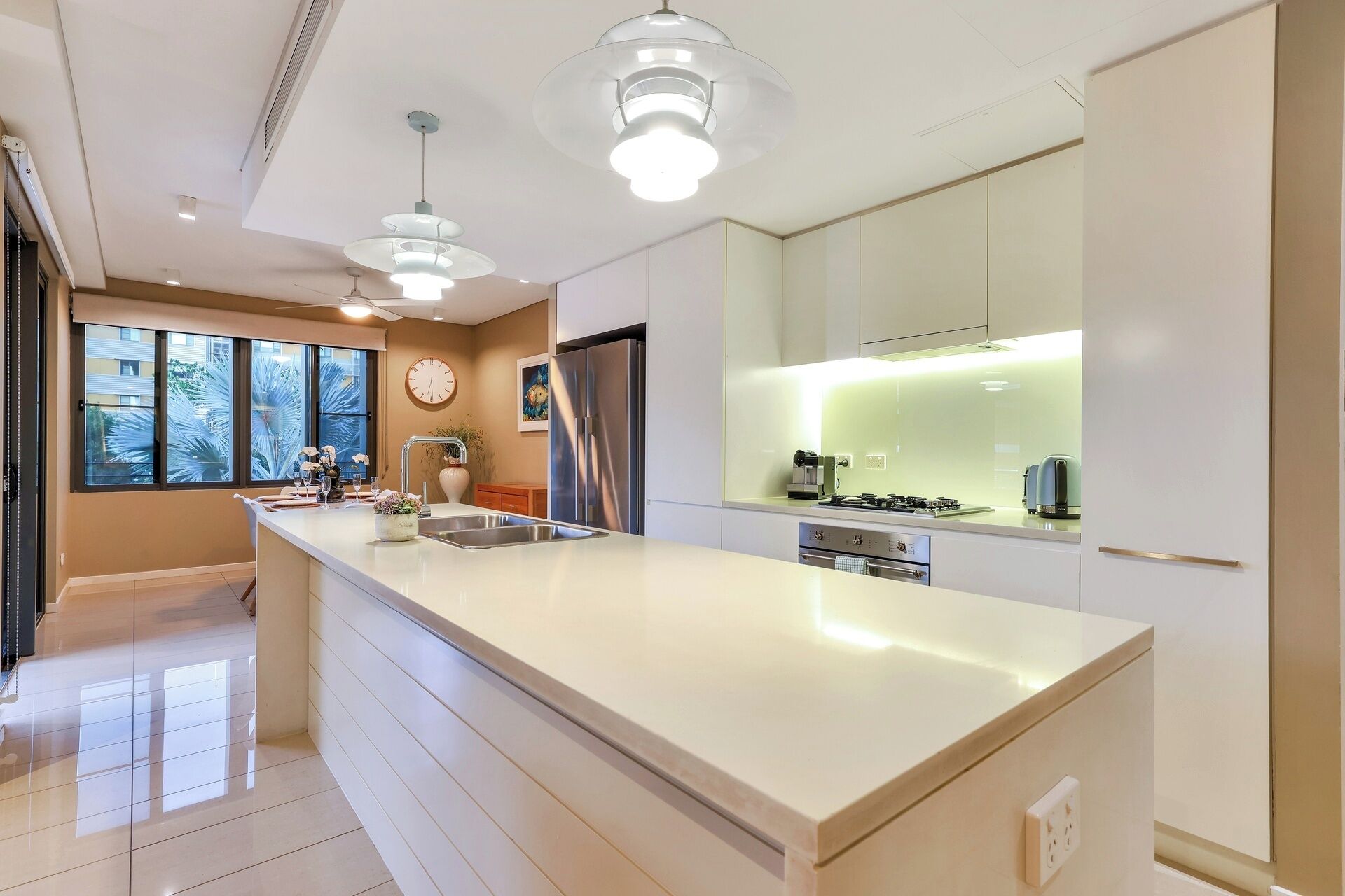 A modern kitchen with a large island, stainless steel appliances, and pendant lighting.