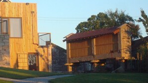 Un edificio rústico con pared de piedra y fachada de madera, que presenta un gran ventanal y una puerta pequeña.