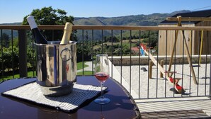 Una terraza con una mesa de metal, una copa de vino y una botella de champán.