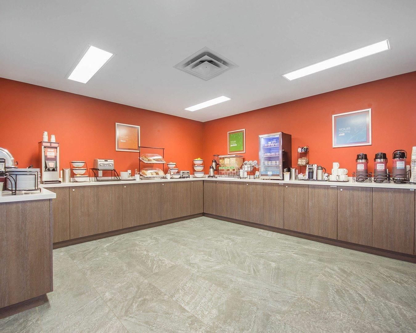 A breakfast bar with a variety of food and drink options, including a coffee machine and a fruit display.