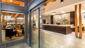 Un moderno vestíbulo de hotel con mostrador de recepción, zona de estar y una pared de piedra.