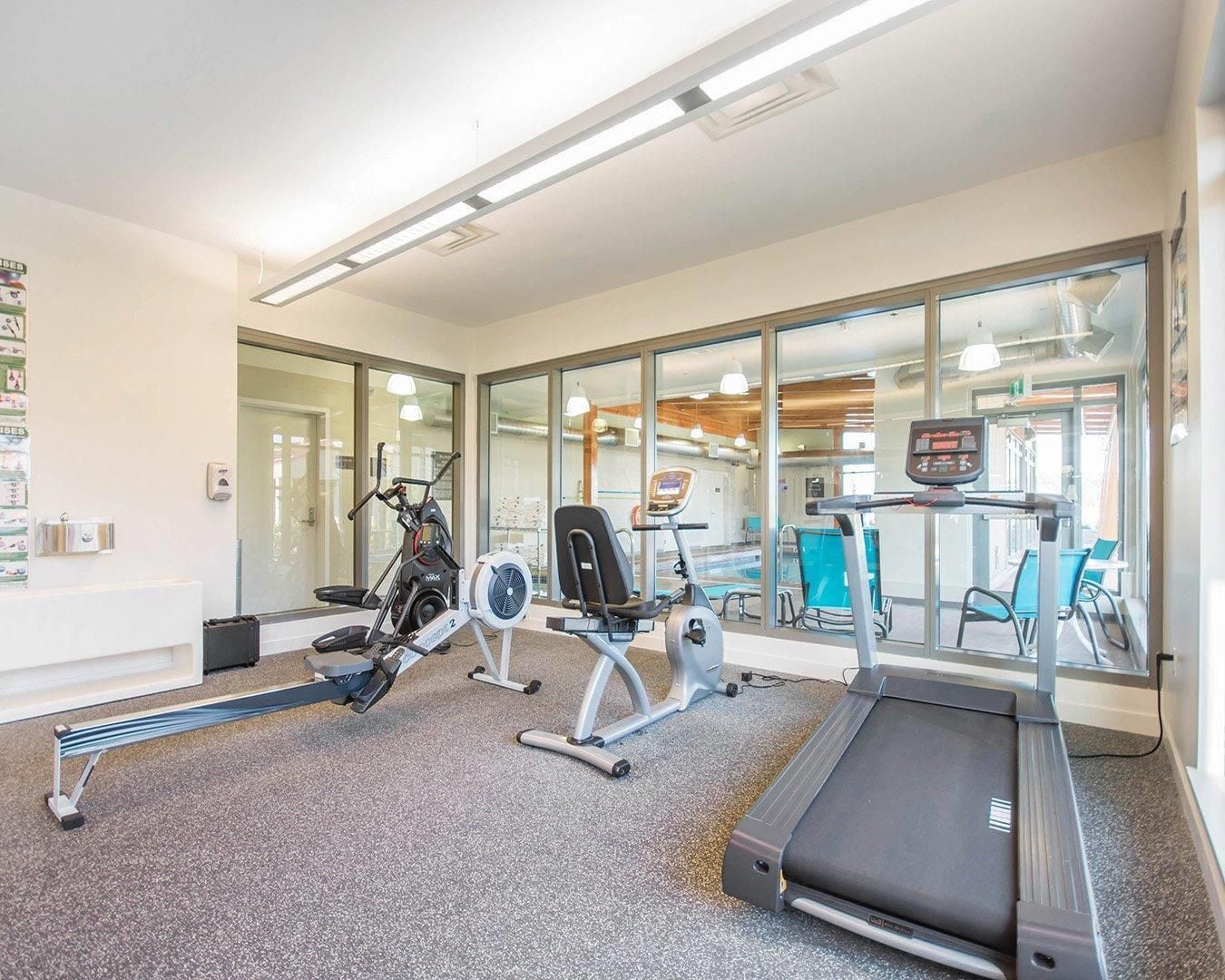 Un gimnasio con máquinas de cardio, una cinta de correr y equipo de ejercicio.