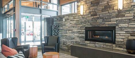 A modern interior with a stone fireplace, leather seating, and a large window.