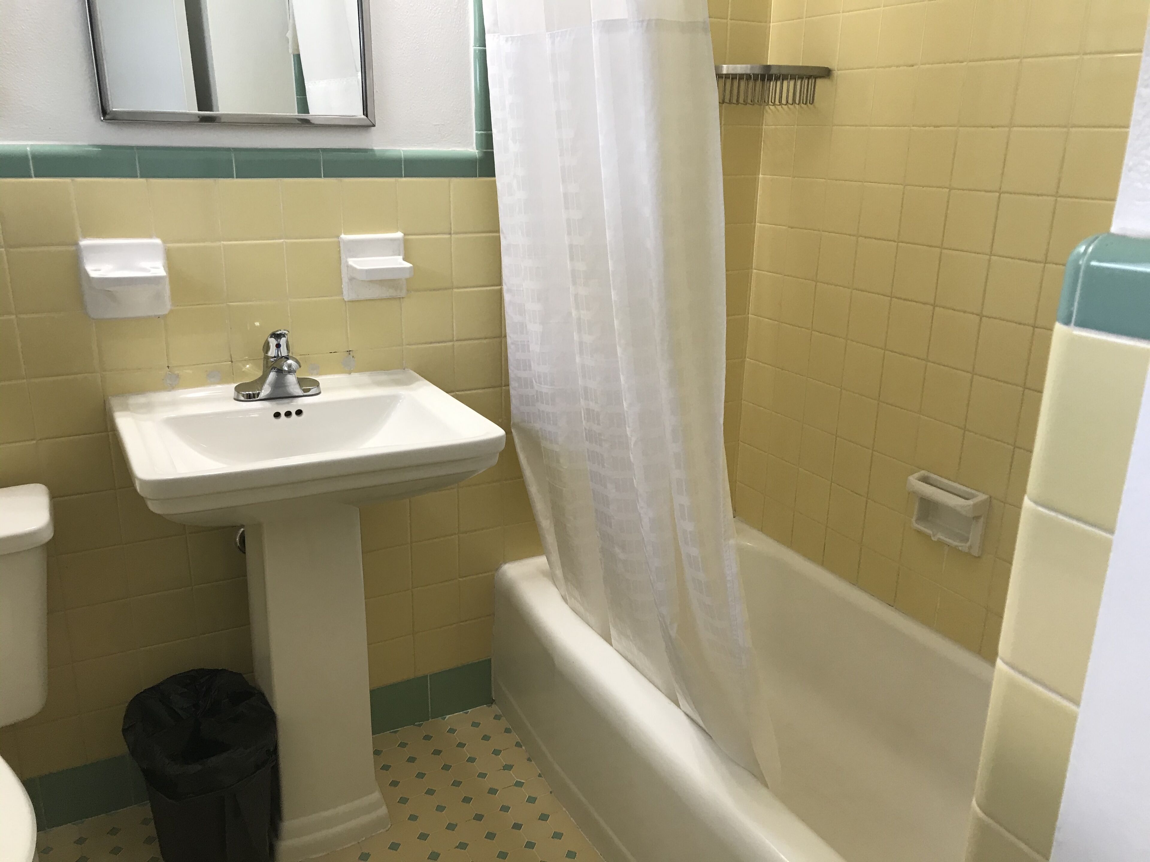 A bathroom with a white sink, a toilet, a bathtub, and a shower curtain.