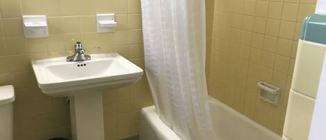 A bathroom with a white sink, a toilet, a bathtub, and a shower curtain.