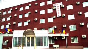 A red building with multiple air conditioning units, a sign reading "HOTEL", and several flags. - Est Hotel Bucharest (Bucharest)