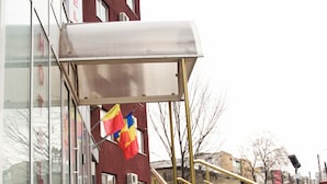 A hotel entrance with a covered staircase, a red building facade, and a blue car parked nearby. - Est Hotel Bucharest (Bucharest)