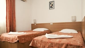 Two single beds with patterned bedding, a wooden headboard, a wall-mounted light, and a framed picture. - Est Hotel Bucharest (Bucharest)