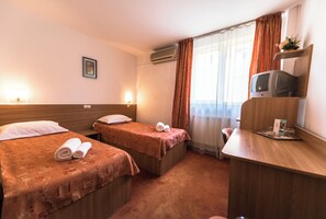 A hotel room with two beds, a desk, a television, and a window with curtains. - Est Hotel Bucharest (Bucharest)