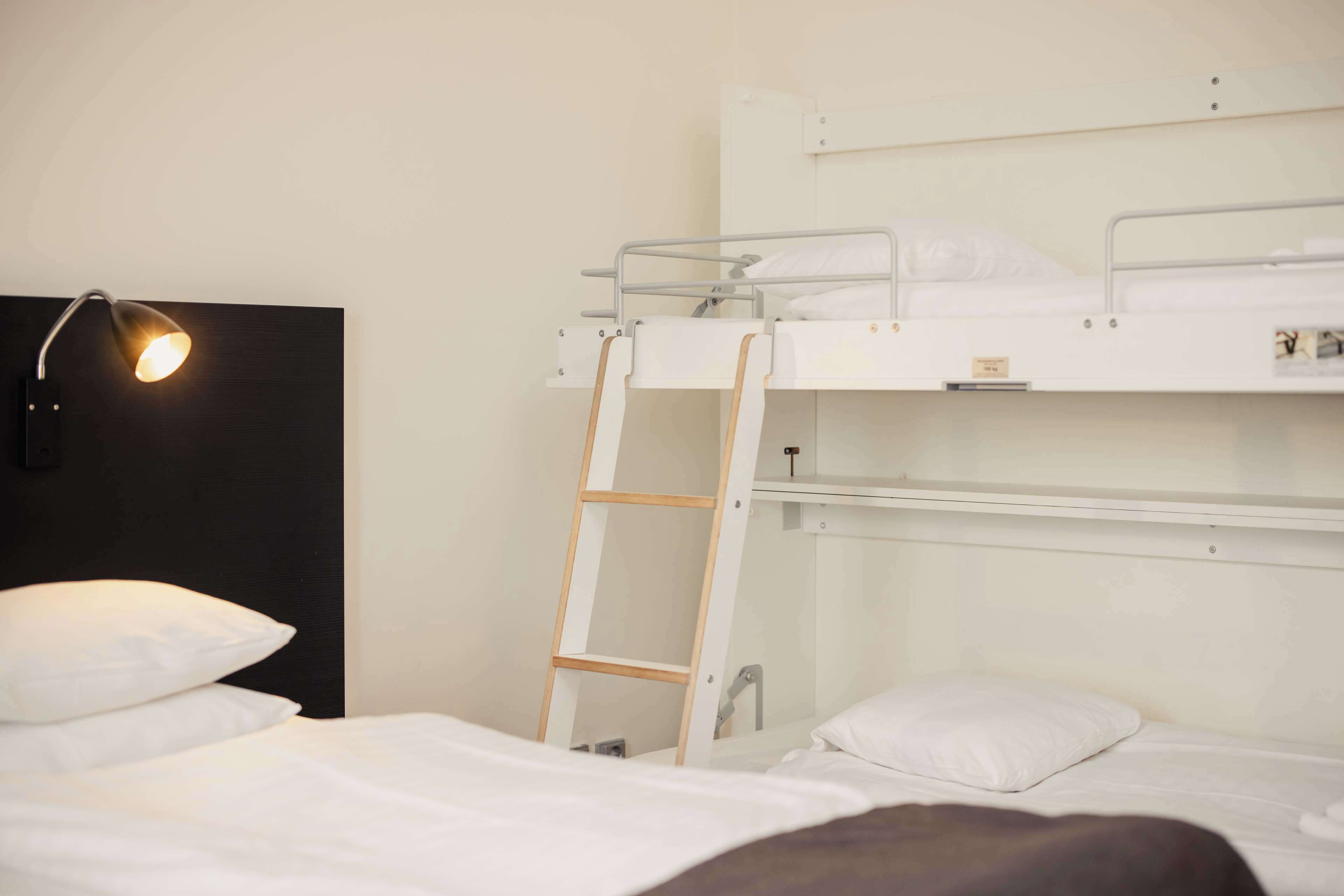 A bunk bed room with a ladder, a desk, and a lamp.