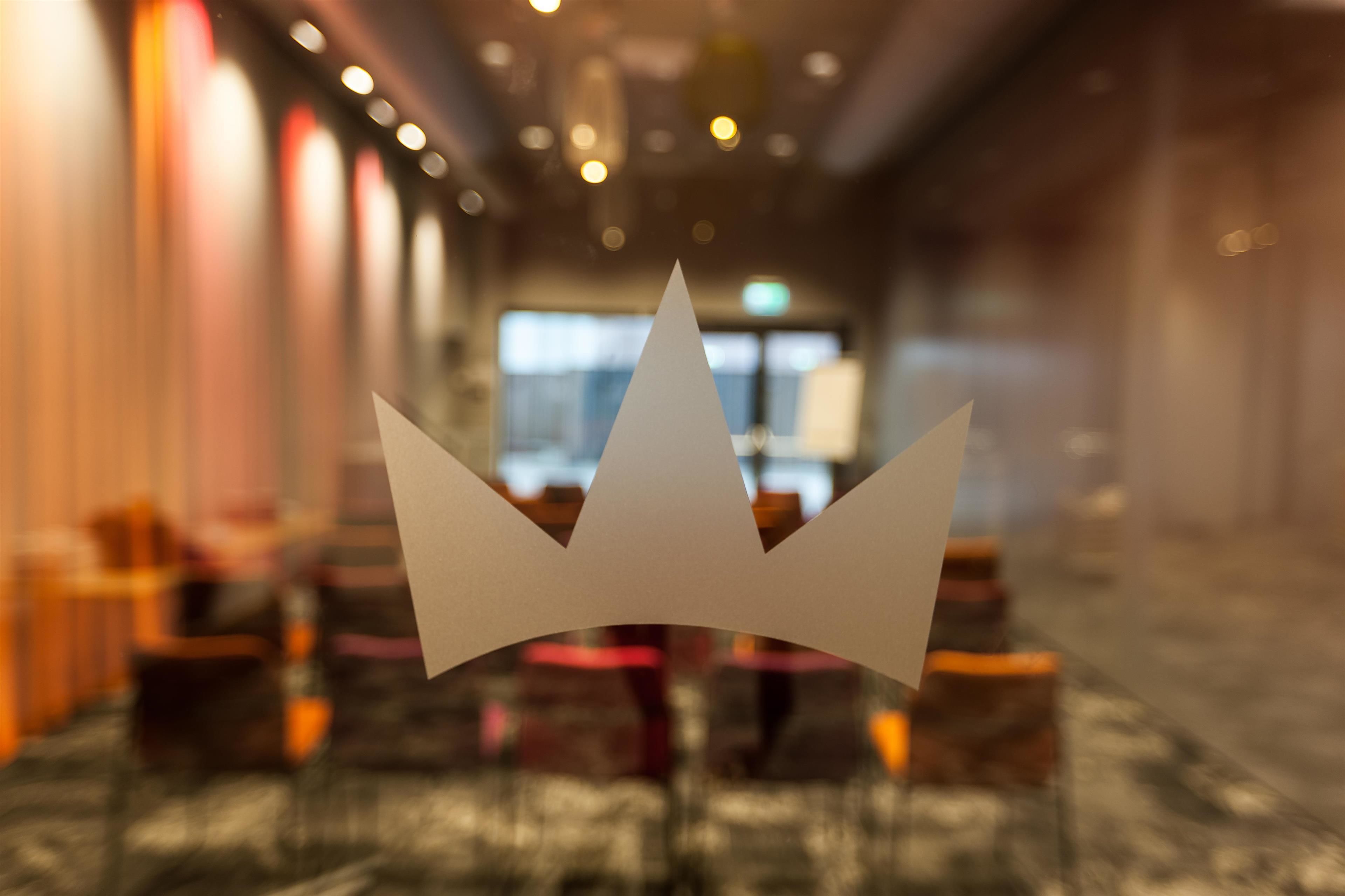 Interior borroso de un hotel con una zona de estar central y un objeto con forma de corona en primer plano.